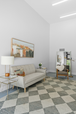 Living Space Grey couch with checkered rug, chair, lamp, and paintings.